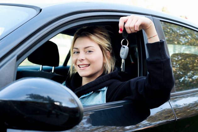 Girl sitting in her car and showing key